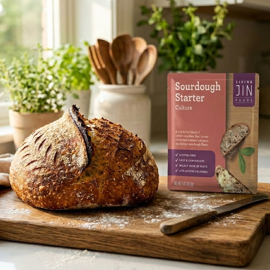 A beautifully baked, rustic gluten-free sourdough bread loaf sitting next to a package of Livingjin Easy Sourdough Starter on a clean kitchen counter.