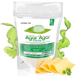 A white product pouch of Living Jin Agar Agar Powder, described as a vegetable gelatin substitute with high gelling properties. The packaging features a clear jelly mold on a green leaf and is surrounded by stylized green seaweed illustrations, with slices of vegan cheese shown in the foreground to illustrate its use as a firming agent.