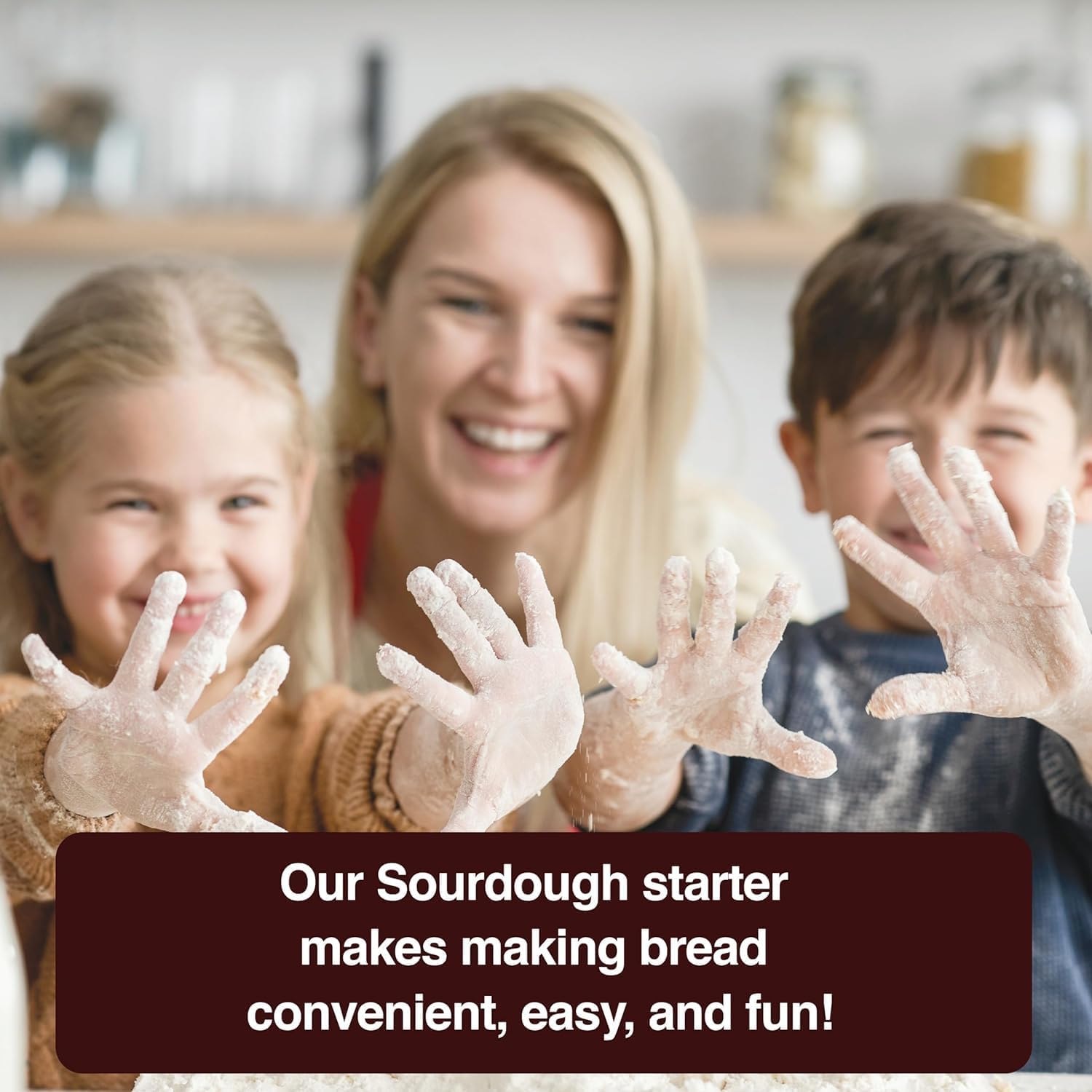 A heartwarming lifestyle image featuring a mother and her two children smiling brightly while baking together. The children hold up their flour-covered hands toward the camera, capturing a messy and joyful moment. A dark banner at the bottom reads, "Our Sourdough starter makes making bread convenient, easy, and fun!", emphasizing the brand's focus on family-friendly kitchen experiences.