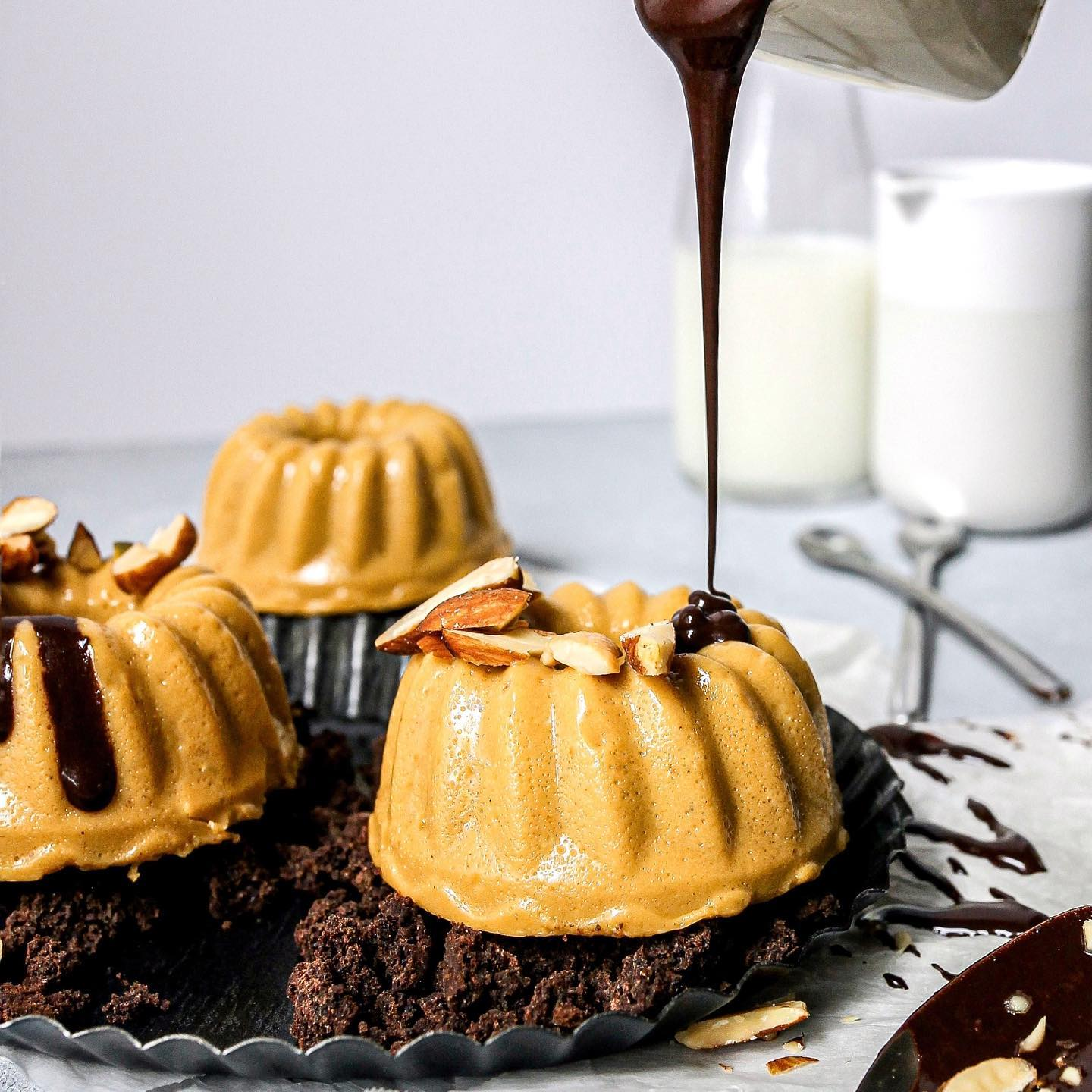 Chocolate and peanut butter dessert being drizzled with chocolate sauce on a white background